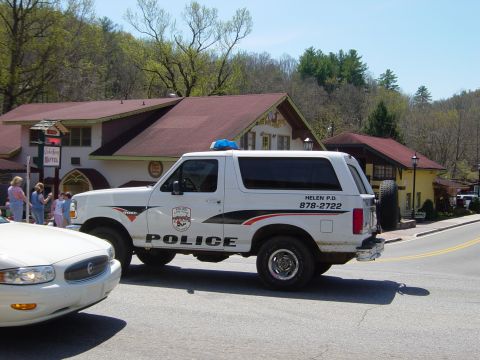 1988 Ford Bronco - A police SUV is parked on the side of the road near a building, with another car in front.