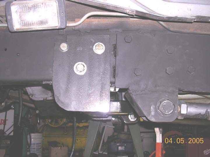 Freshly painted black frame with bolted bracket on jack stands, underside view