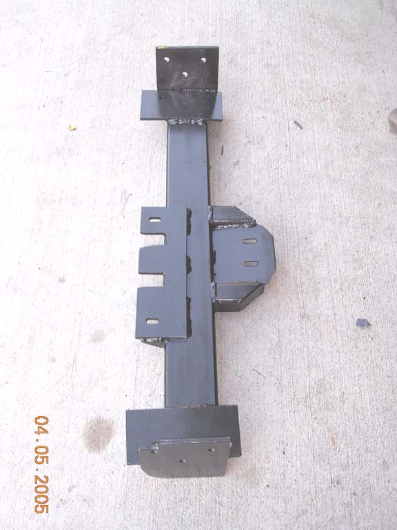 Custom welded steel bracket assembly painted black, laid on concrete
