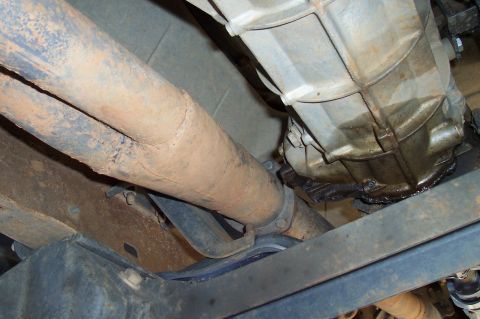 1994 Ford F-150 - Underside view of an exhaust pipe and transmission housing, with visible rust and oil leaks.