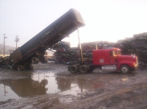 1995 Ford Bronco - A red semi-truck unloads scrap metal into a large pile at a junkyard.