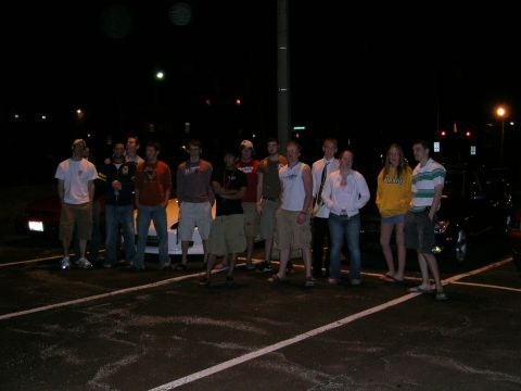 1994 Ford Probe - A group of people gathered in a parking lot at night, with several vehicles visible in the background.