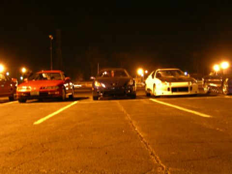 1994 Ford Probe - Several sports cars are parked in a lot under artificial lighting at night.