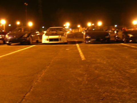 1994 Ford Probe - Multiple cars are parked in a lot at night, illuminated by overhead lights.