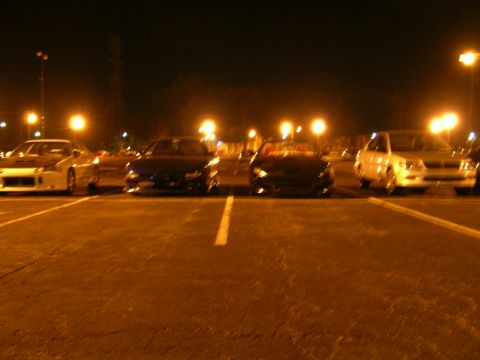 1994 Ford Probe - Multiple vehicles are parked in a lot at night, illuminated by overhead lights.