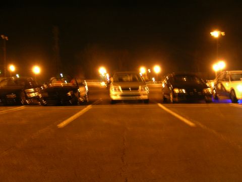 1994 Ford Probe - A group of cars are parked in a lot under the glow of streetlights at night.