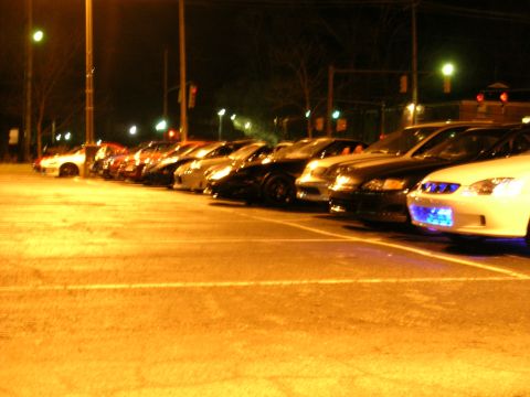 1994 Ford Probe - A row of cars are parked together at night, with one vehicle displaying blue underglow lighting.