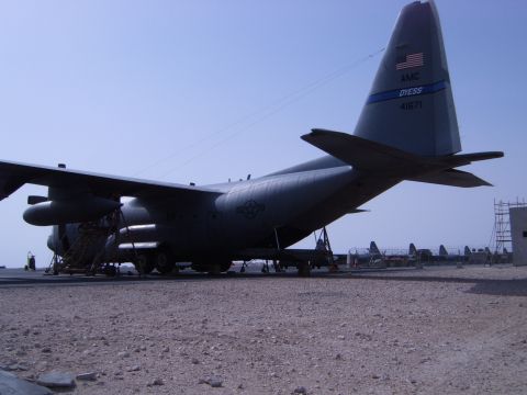 1988 Ford Bronco - A large military cargo plane sits on a dusty airfield under a clear blue sky.
