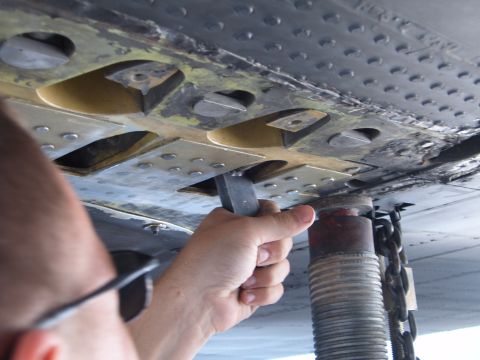 1988 Ford Bronco - A hand uses a tool to work on the underside of a vehicle, revealing complex mechanical components.