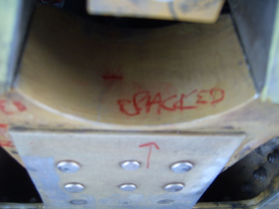 Underside of a vehicle part with red marker text 'CRACKED' and an upward arrow