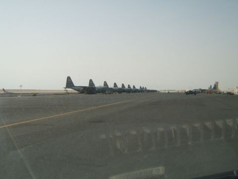 1988 Ford Bronco - Multiple military cargo planes are lined up on an airfield tarmac under a hazy sky.