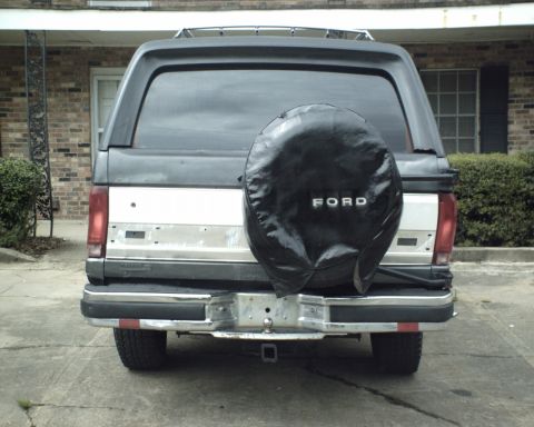 1987 Ford Bronco - The rear of a 1987 Ford Bronco is visible, a spare tire cover with the Ford logo.