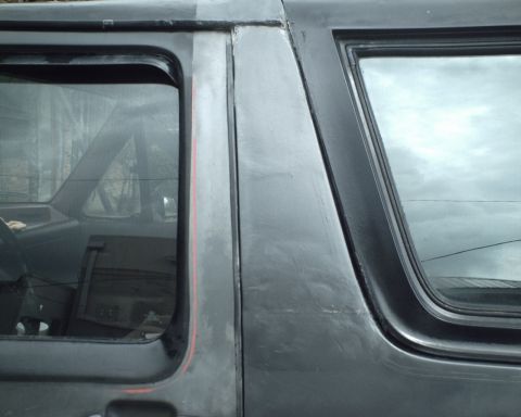 1987 Ford Bronco - Close-up of the side of a dark SUV, showing the rear door and window area.