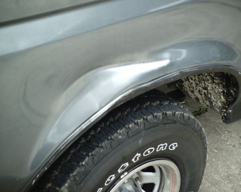 1987 Ford Bronco - The fender of a gray 1987 Ford Bronco shows a noticeable dent above the wheel well.