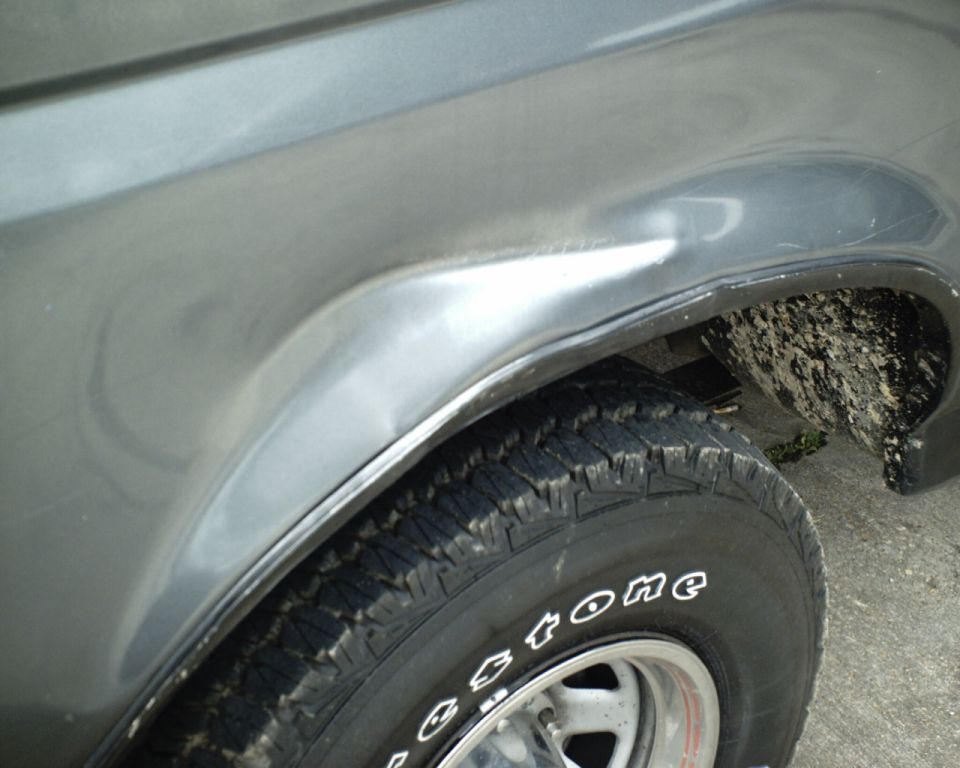 Gray 1987 Ford Bronco fender with a dent above the wheel well and a Firestone tire