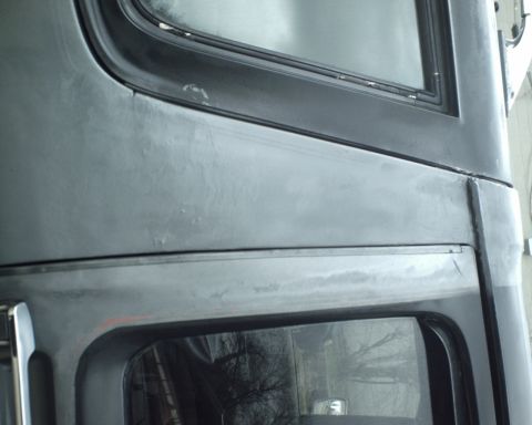 1987 Ford Bronco - Detail of a vehicle body panel, showing window trim and a watermark.