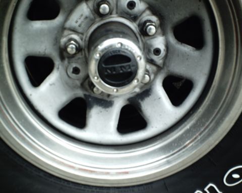 1987 Ford Bronco - A close-up view of a vehicle's wheel hub, a black center cap with visible text.
