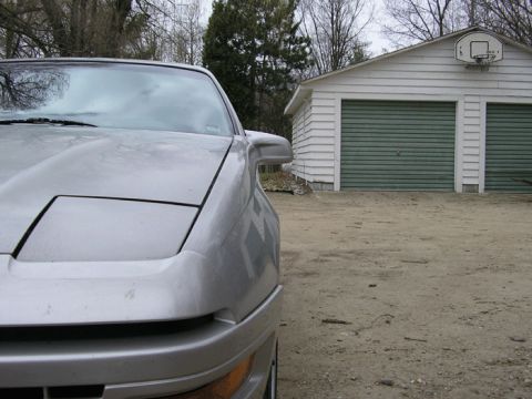 1990 Ford Probe - A silver car is parked in front of a detached garage on a cloudy day.