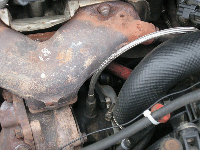 Close-up of a rusty exhaust manifold and some engine components