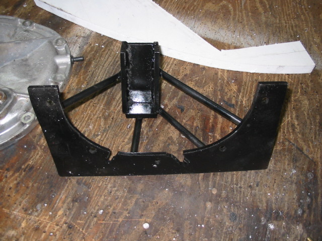 Black metal automotive part with a silver differential housing on a wooden surface