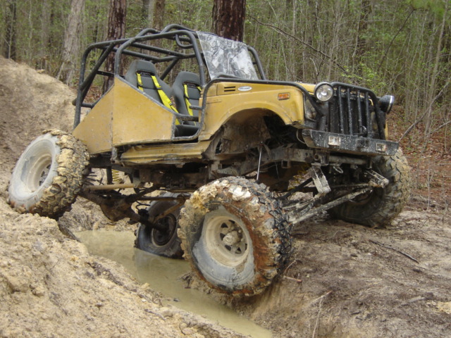 Yellow off-road buggy with roll cage navigating muddy terrain