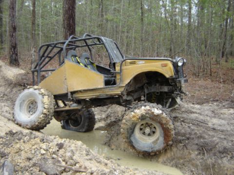 1989 Ford Bronco - Modified off-road buggy navigating a muddy trail with large tires.