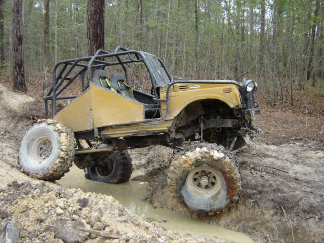 Yellow off-road buggy with roll cage stuck in mud on a trail