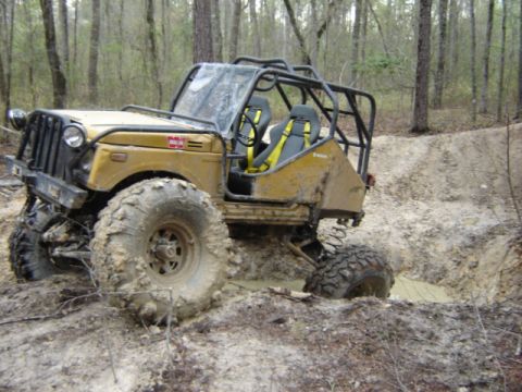 1989 Ford Bronco - This heavily modified off-road vehicle is navigating a muddy trail.