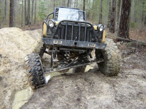 1989 Ford Bronco - This heavily modified off-road vehicle is shown navigating a challenging muddy terrain.