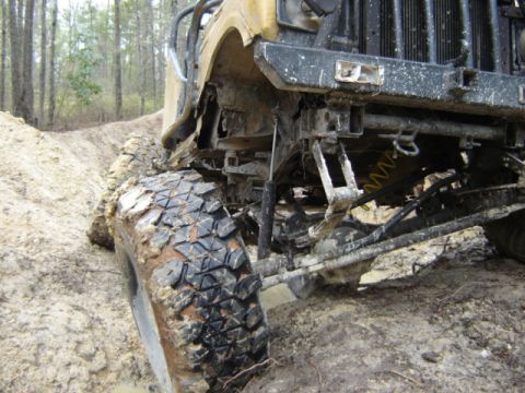 1989 Ford Bronco - Close-up of off-road vehicle suspension and tire in muddy terrain.