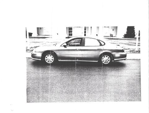1998 Ford Taurus - A 1998 Ford Taurus is shown from the side, parked on a paved surface in front of a building.