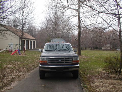 1979 Ford Bronco - A Ford F-Series truck is parked in a driveway with a house and trees in the background. Another vehicle is partially visible.