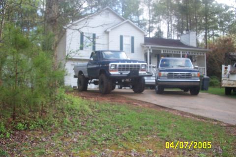 1979 Ford F-150 - Two Ford trucks, a lifted F-150 and another pickup, are parked in front of a house.