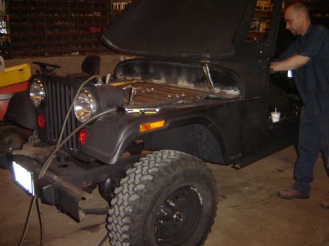 1992 Ford Bronco - A man works on a black Jeep CJ in a garage setting.