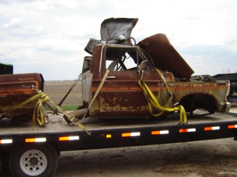 1992 Ford Bronco - This heavily rusted pickup truck cab and bed are being transported on a flatbed trailer.