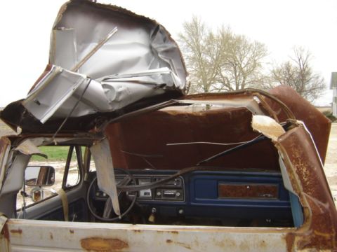 1992 Ford Bronco - The interior of a heavily damaged truck shows the dashboard and steering wheel beneath a collapsed roof.