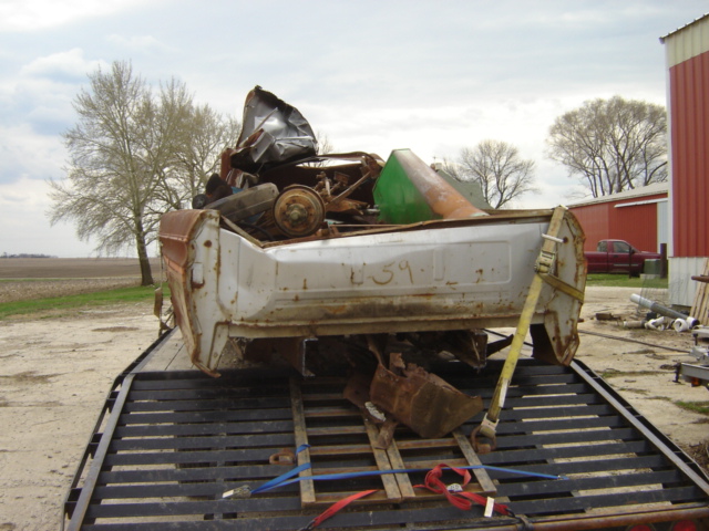 White truck bed with rust, strapped to a flatbed trailer. Visible number '259' on the side