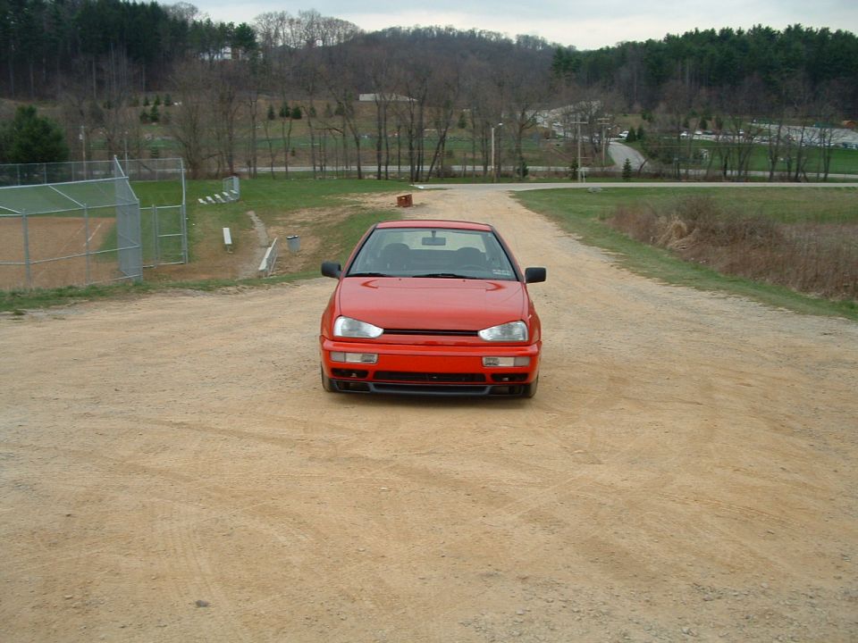 Red Volkswagen Golf Mk3 parked on a dirt road facing forward