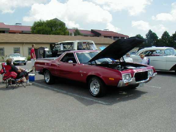 Dark red 1972 Ford Ranchero with hood open at an outdoor car show, 3/4 front passenger view
