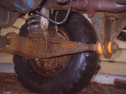 1985 Ford Bronco - Rusty rear axle and suspension parts, including a coil spring and control arm with bushings.