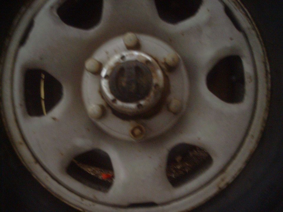 Close-up of a white wheel hub with five lug nuts
