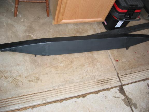Black plastic rocker panel side molding lying on garage floor with mounting clips visible