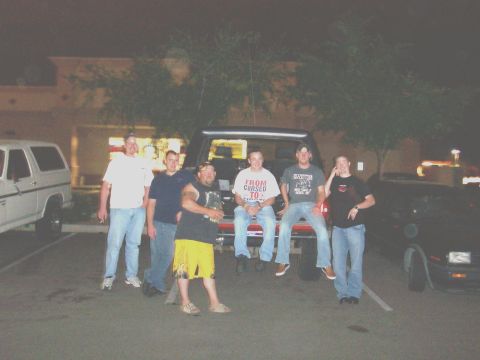1994 Ford Bronco - A group of friends gathered around vehicles at night, with one man wearing a shirt that says 'FROM CURSED TO'.