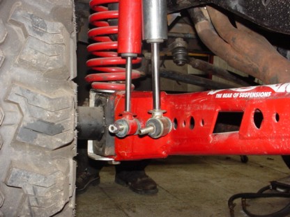 1988 Ford Bronco - Close-up view of red suspension components and a large tire, with visible text indicating "THE REAR OF SUSPENSIONS".