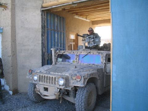 1979 Ford Bronco - A Humvee equipped with a machine gun is seen exiting a structure.