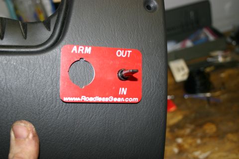 2003 Jeep TJ - A close-up of a vehicle's interior panel displays a red switch plate with operational labels and a toggle switch.