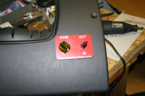 2003 Jeep TJ - A red switch plate with 'ARM', 'OUT', and 'IN' labels is installed on a vehicle's interior panel.