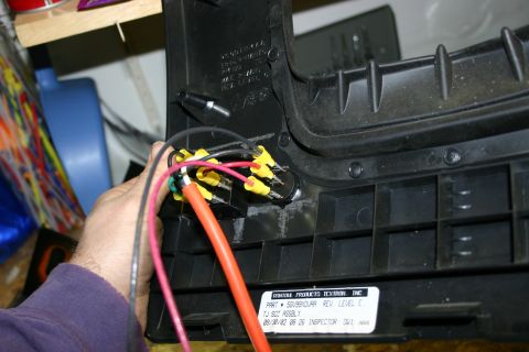 2003 Jeep TJ - A close-up shows a hand connecting electrical wires to a switch assembly on a black plastic component.