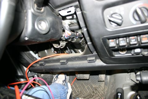 2003 Jeep TJ - A close-up view of the dashboard interior of a 2003 Jeep TJ, showing exposed wiring and a person's foot near the pedals.