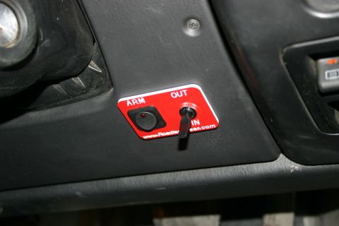 2003 Jeep TJ - Interior view of a vehicle dashboard a red switch panel with labels for ARM/OUT and IN.